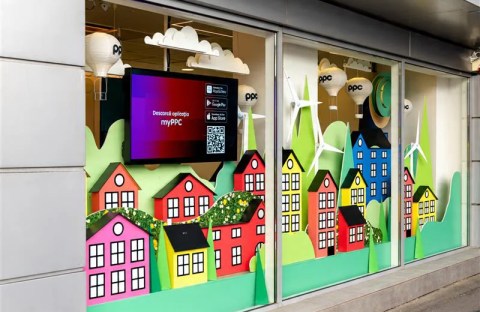 Vitrină magazin PPC Brașov decorată cu căsuțe colorate, turbine eoliene și baloane cu aer cald pentru atelierele de copii