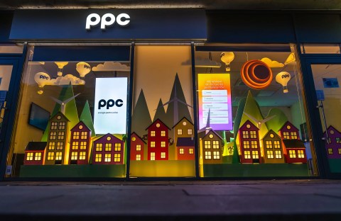 Vitrina magazinului PPC Craiova cu decor tematic de energie verde: căsuțe colorate și turbine eoliene